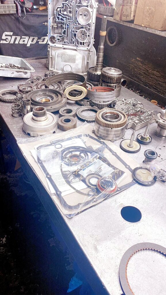 Transmission case standing open with drums, gears and a seal and gasket kit on the bench at Tri-Star Transmissions