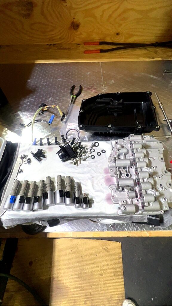 Valve body with its solenoids in a row and transmission oil pan on the bench at Tri-Star Transmissions